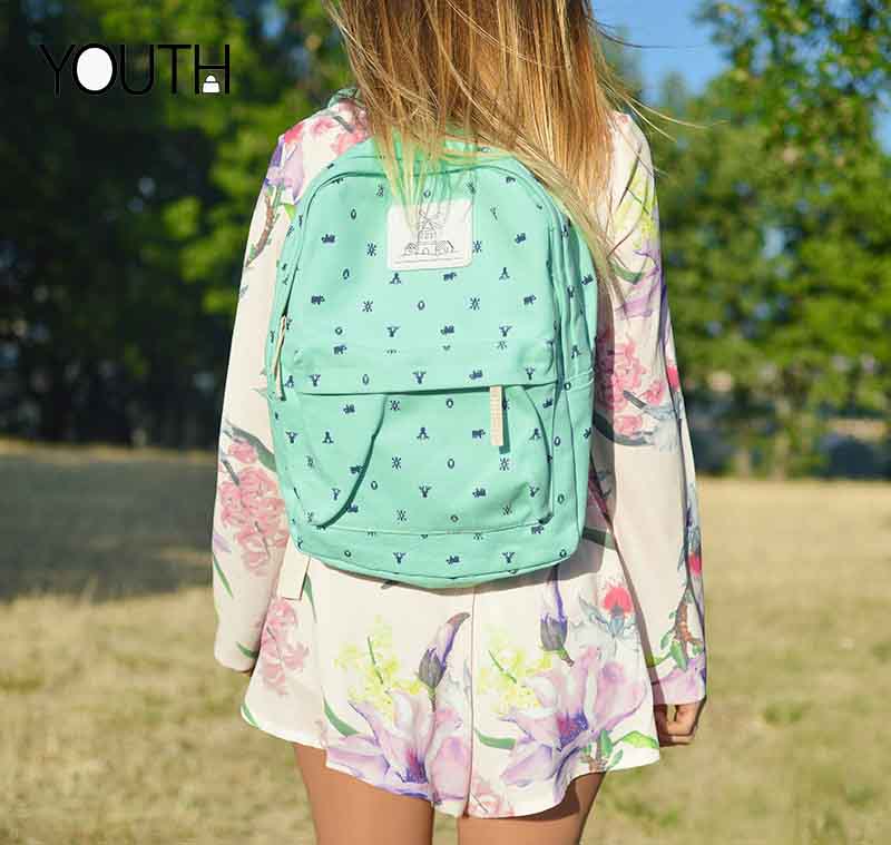 A cute girl wearing a school backpack on the grass