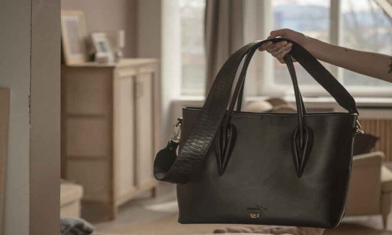 A black leather tote bag holded by an women in the house