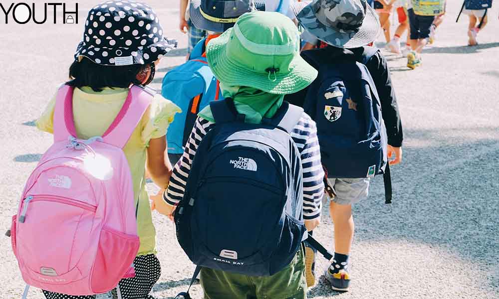 A few girls and boys wearing different shool backpacks after school