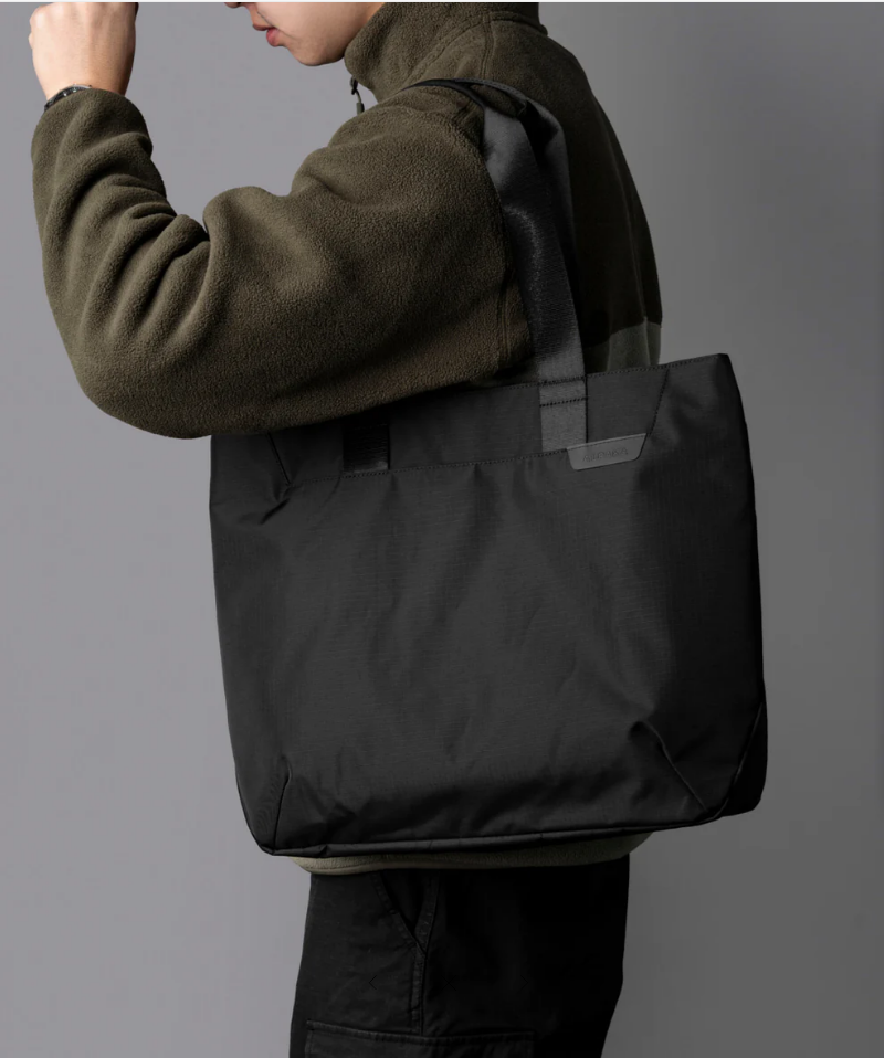 A view of a model wearing a black alpaka elements tote bag