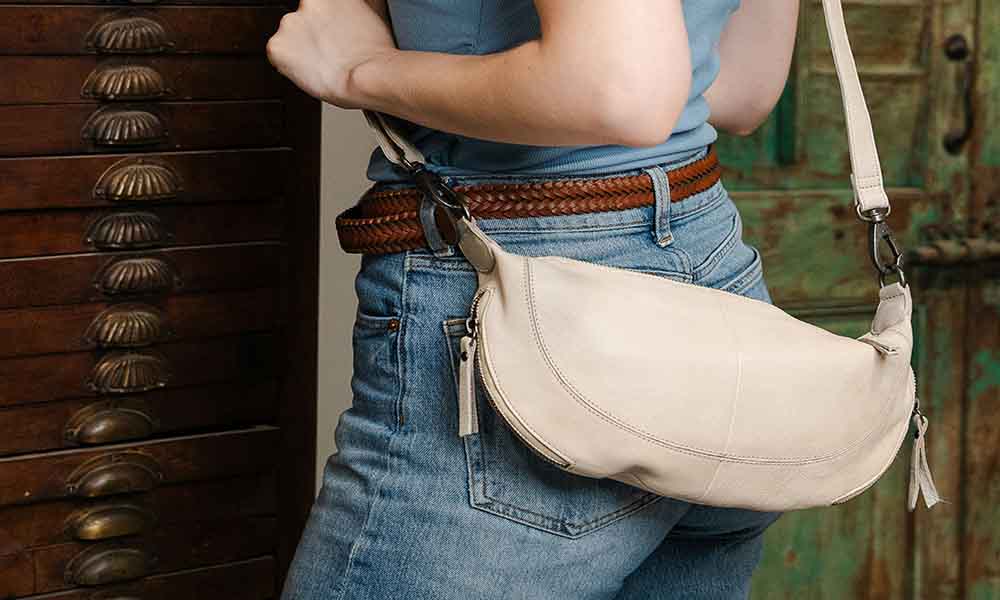 A lady with denim jens pant wearing a beige crossbody bags for showing