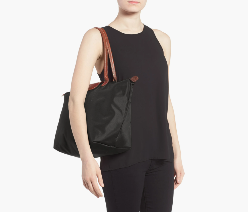 A lady model in black clothes wearing a black longchamp le pliage tote bag