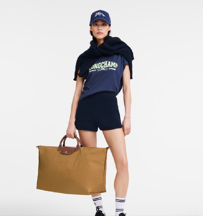 A yong lady holding a brown longchamp le pliage tote bag for showing