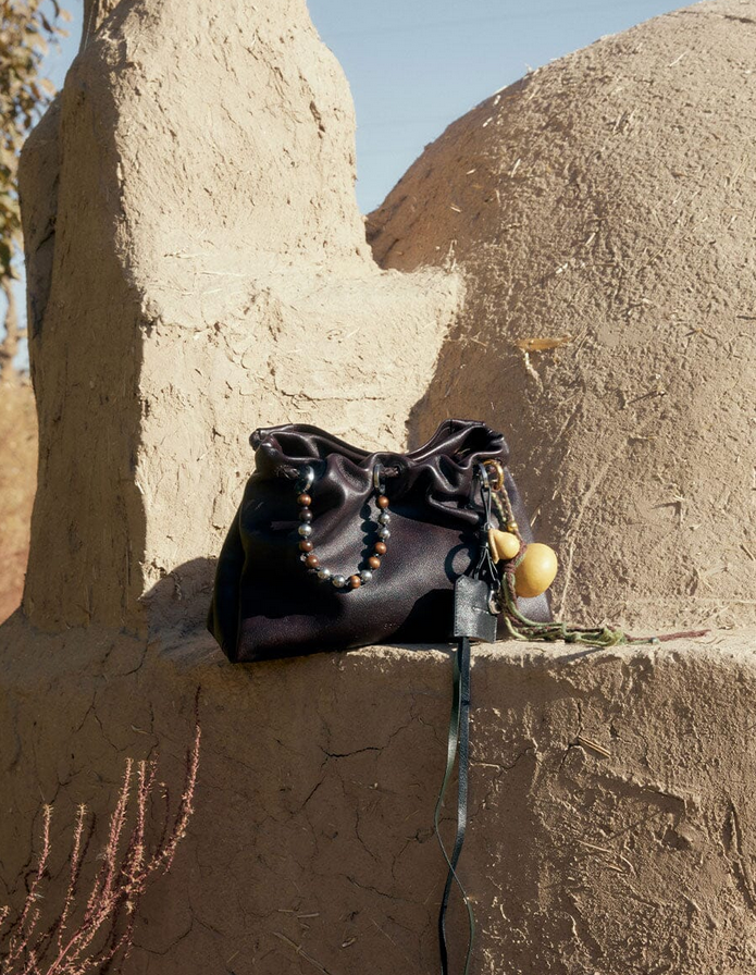 A black songmont gather bag sitting on a dessert for showing